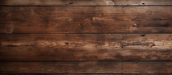 A close up of a hardwood wall with a brown wood stain in an amber hue. The rectangular planks create a beige flooring with a blurred background