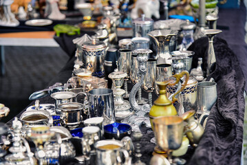Fototapeta na wymiar Antique market, shelf with silver vases, jugs, mugs and stands, candlesticks, metal products.