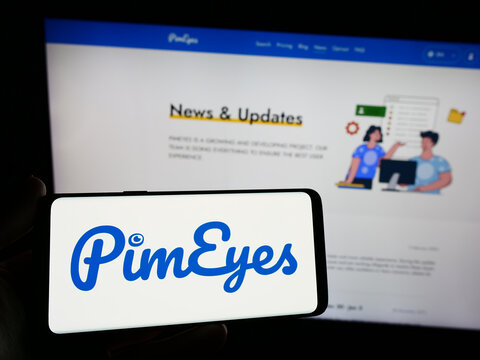Stuttgart, Germany - 03-13-2024: Person holding smartphone with logo of facial recognition search company PimEyes in front of website. Focus on phone display.