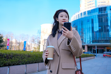 Young Woman with Coffee Navigating City on Smartphone