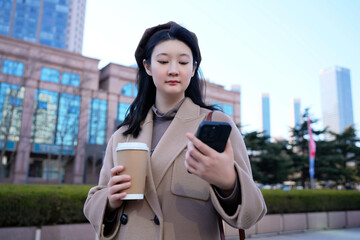 Urban Lifestyle - Young Woman with Coffee Using Phone