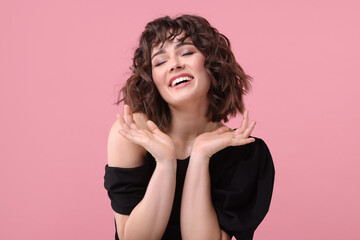 Portrait of beautiful young woman with wavy hairstyle on pink background