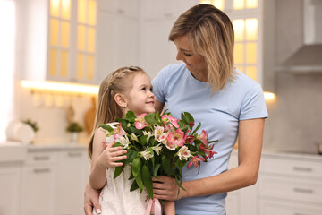 Little daughter congratulating her mom with bouquet of alstroemeria flowers in kitchen. Happy Mother's Day