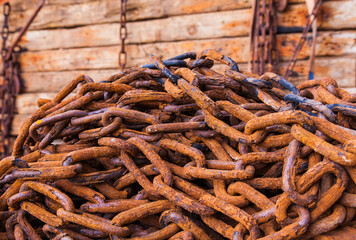 Rusty chains lie on wooden logs and hold them together close-up.
