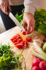 A close up of girl's or woman's hands peeling and cutting vegetables with knife making salad	