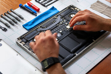 Computer technician fixing a PC, implementing software, cleaning technological parts, quality control