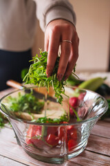 A close up of girl's or woman's hands peeling and cutting vegetables with knife making salad	