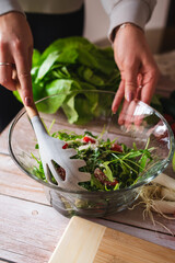 A close up of girl's or woman's hands peeling and cutting vegetables with knife making salad	
