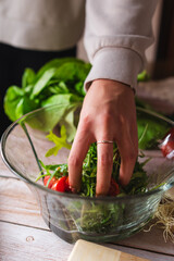 A close up of girl's or woman's hands peeling and cutting vegetables with knife making salad	