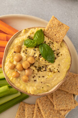 A dish of hummus with a side of carrots, celery and more hummus on a plate