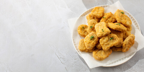 Delicious golden chicken nuggets on a plate on the table. Fast food, menu. Copy space