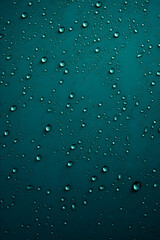 A mesmerizing pattern of crystal clear water droplets resting on a deep teal colored surface