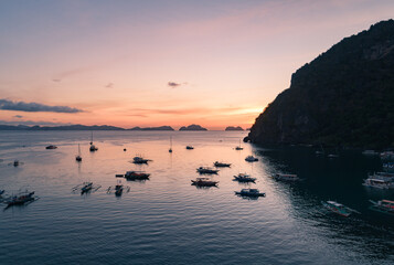 Aerial view of cliffs in the sea, yachts are sailing nearby, mountains covered with tropical...