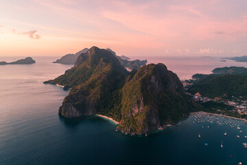 Aerial view of cliffs in the sea, yachts are sailing nearby, mountains covered with tropical...