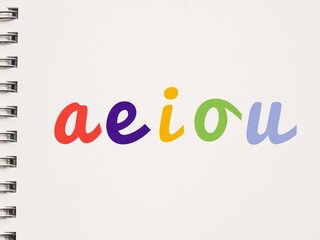 Colorful handwritten AEIOU lowercase vowels on a notebook - obrazy, fototapety, plakaty