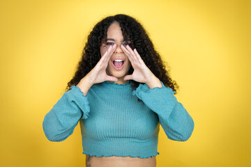 African american woman wearing casual sweater over yellow background shouting and screaming loud to...