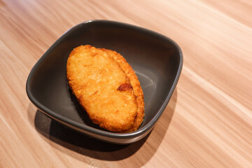 close up of two pieces of fried hash-brown on a black plate placing on the wooden table 
