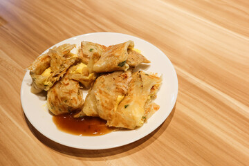 Close up of delicious Taiwanese omelette, egg pancake roll cut into pieces with ham, soy sauce on a white plate. There is copy space. The food is for breakfast