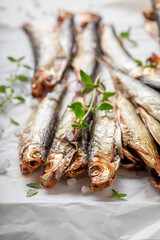 Fresh and salty smoked sprats on white paper - 766308059