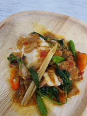 Tumis Cumi Cabe or stir fried fresh squid with green chili and red thai chili, served in white bowl. Indonesian traditional dish. Selective focus.
