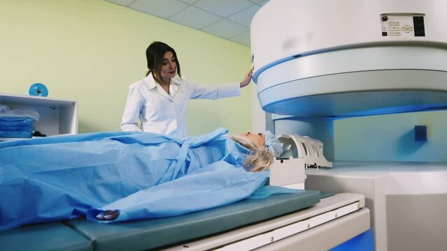 The girl lies in an MRI machine. A doctor performs an MRI on a patient in the clinic. Magnetic resonance imaging in the study of the human body. Modern technologies in medicine.