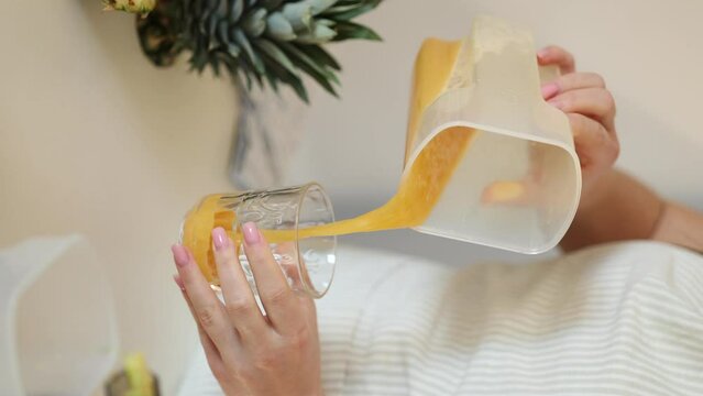 Middle selection of woman pouring fresh juice into glass. Homemade vegan beverage. Orange drink