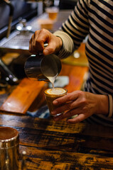 barista making a latte in a cup in a coffee shop