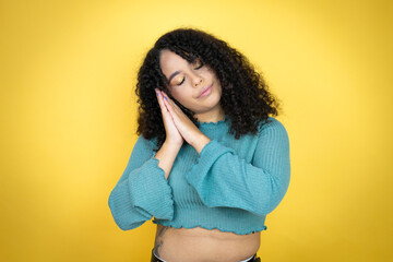 African american woman wearing casual sweater over yellow background sleeping tired dreaming and...