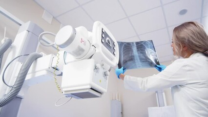 Doctor with x-ray of lungs in hands in modern medical radiology hospital. The doctor analyzes the condition of the lungs. The virus attacks the lungs. COVID-19 and medical examinations.