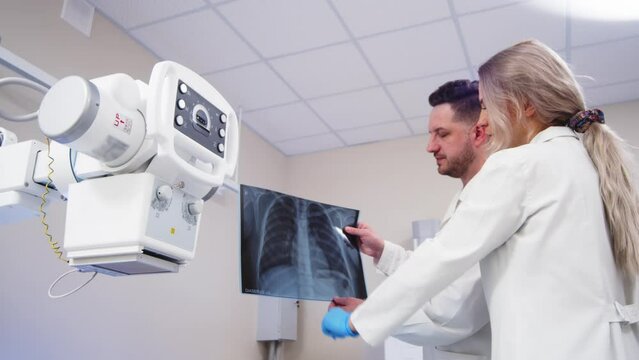 Specialists consult in the X-ray room. Lung diseases, inflammation and colds after Covid. Medical coaching and collaboration to achieve patient outcomes.