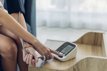 Foto op Plexiglas Woman measuring blood pressure by using digital sphygmomanometer at home. Woman using medical device to measure blood pressure. © kanpisut