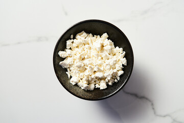 Cottage cheese in the black plate on white marble backgorund. Tasty, full of protein and healthy...