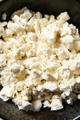 Cottage cheese in the black plate on white marble backgorund. Tasty, full of protein and healthy breakfast idea.