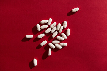 White Medical Pills on vibrant red background. 80s and 90s retro style, hard light and contrast...