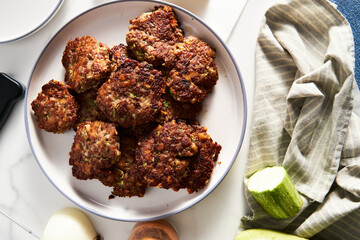Beef, zucchini and cheddar cheese patties or cutlets on white plate. Dinner meat concept, full of proteins.