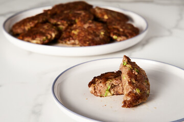 Beef, zucchini and cheddar cheese patties or cutlets on white plate. Dinner meat concept, full of proteins.