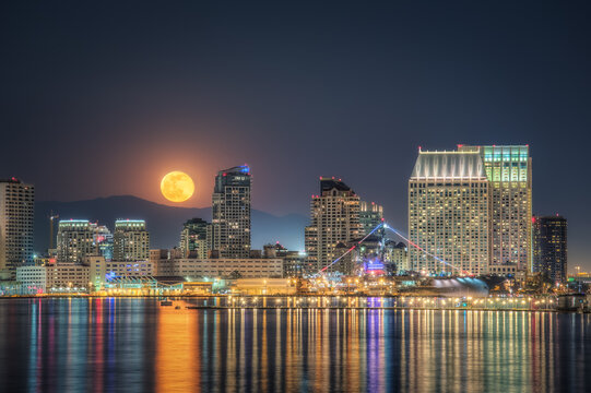 Fototapeta San Diego downtown skyline and full moon over water at night