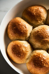 Burger Buns or mini buns in the round baking pan. Very soft Freshly Baked Homemade, buttered. White marble background. Minimalistic photo. Top view. Close Up