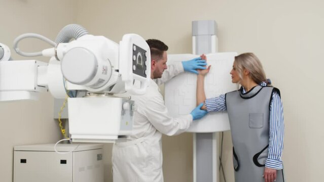 The doctor prepares the patient for an X-ray of the arm. Preparing for radiography. Examination of a broken or bruised arm. Medical examination, hospital trauma department.