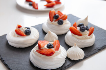 Pavlova dessert with fresh berries. Meringue (beze) with strawberries and blueberries.  - obrazy, fototapety, plakaty