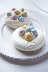 Pavlova dessert with sweet Easter Eggs. An interesting meringue dessert for the Easter table - obrazy, fototapety, plakaty