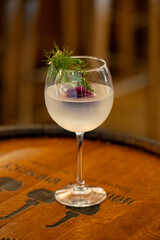 Clear cocktail in a stemmed globe infused with rose and garnished with dill