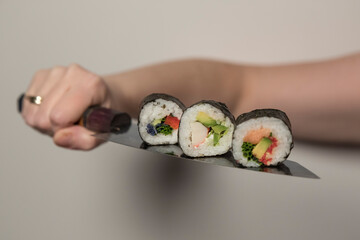 Kawałki rolek sushi na japońskim nożu. - obrazy, fototapety, plakaty