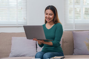 Woman is sitting on a couch holding a laptop