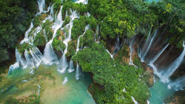 Tropical forest and mountain landscape with streams of water and waterfalls. Cascades flow among lush greenery in spring or summer.