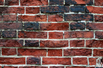 Texture of old rough damaged red brick wall with black stains
