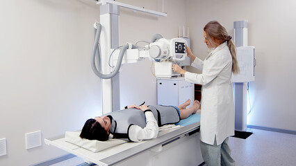 A specialist doctor in an X-ray room, a radiologist sets up a machine for radiography of a patient and makes a scan. The concept of medical technologies, modern medical equipment.