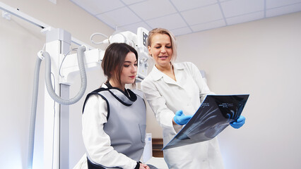 Fototapeta premium Patient consultation in a modern clinic against the background of x-ray equipment. Medical consultation, modern medical technologies.