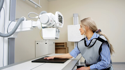 The doctor prepares the patient for an X-ray of the arm. Preparing for radiography. Examination of...