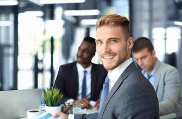 Businessman with colleagues in the background in office.